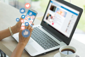 Cell phone and laptop screens open to Facebook business ad center for small businesses and customer liking Facebook posts