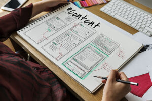 A person in a red shirt sitting at a table in Effingham, IL, and creating custom website content on a large notebook.