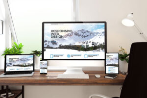 A wooden desk with a desktop computer, laptop, and smartphone open to a responsive web design from a digital marketing company in Champaign, IL.